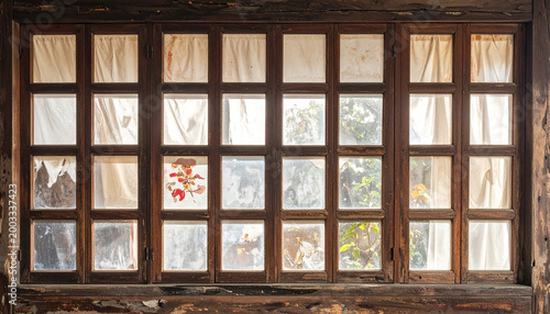 Wooden framed window with multiple panes and translucent curtains indoors