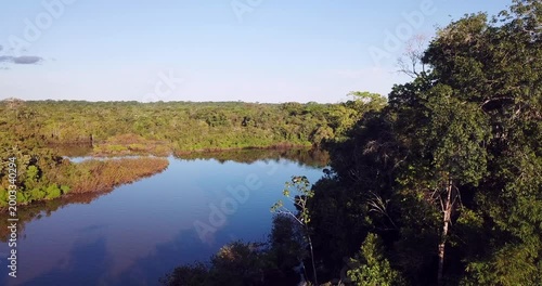 Aerial view of Amazon river at sunset flying over rainforest and water with Puente Nanay bridge near Iquitos Peru smooth drone shot 4K