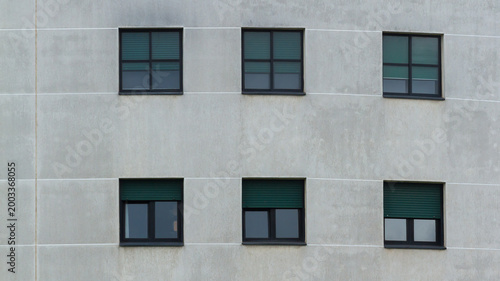Modern residential building facade with geometric window pattern on gray concrete wall
