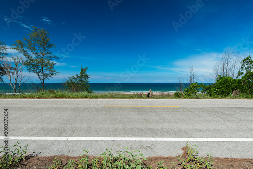 Side view of asphalt road with beach on sea and beautiful blue sky. Road background.