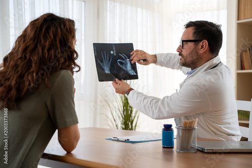 Fotografie Physician explaining hand radiograph to patient during clinic examination