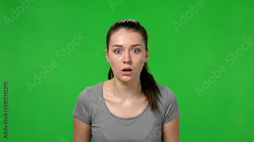 Startled Expression: Portrait of a woman with wide eyes, her face reflecting shock and surprise against a vibrant green backdrop. Capturing the raw emotion of being startled.