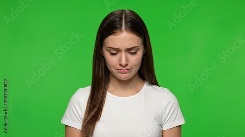 Melancholy Reflection: Portrait of a woman expressing deep sadness and reflection, conveying vulnerability and raw emotion, against a vivid green backdrop.
