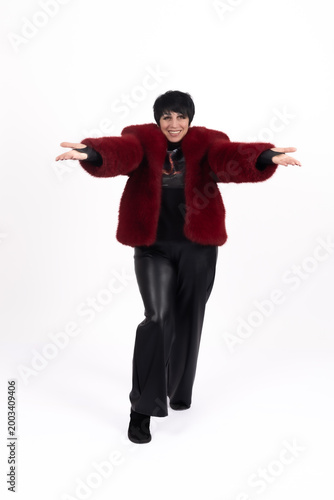 Fotografia Confident woman in red fur coat spreading arms wide