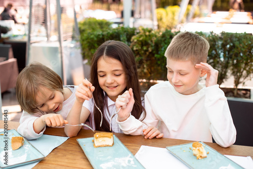 Siblings or friends children sharing dessert enjoying summer holidays