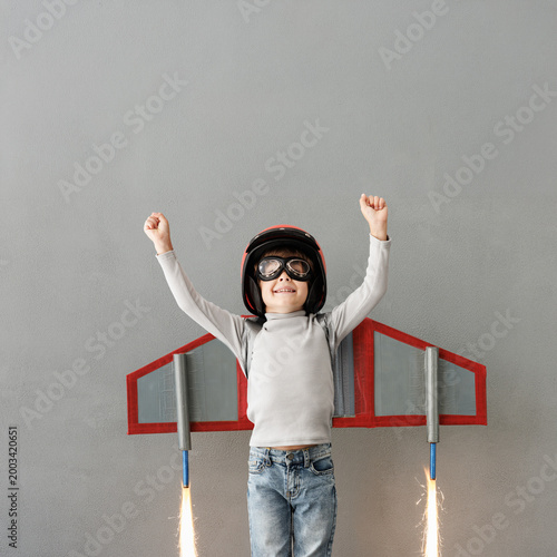 Happy child pretend to be astronaut. Funny kid with paper rocket. Little boy playing indoors