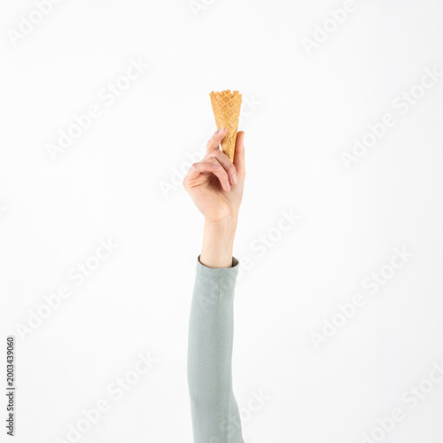 Hand holding an empty waffle ice cream cone against a clean white background