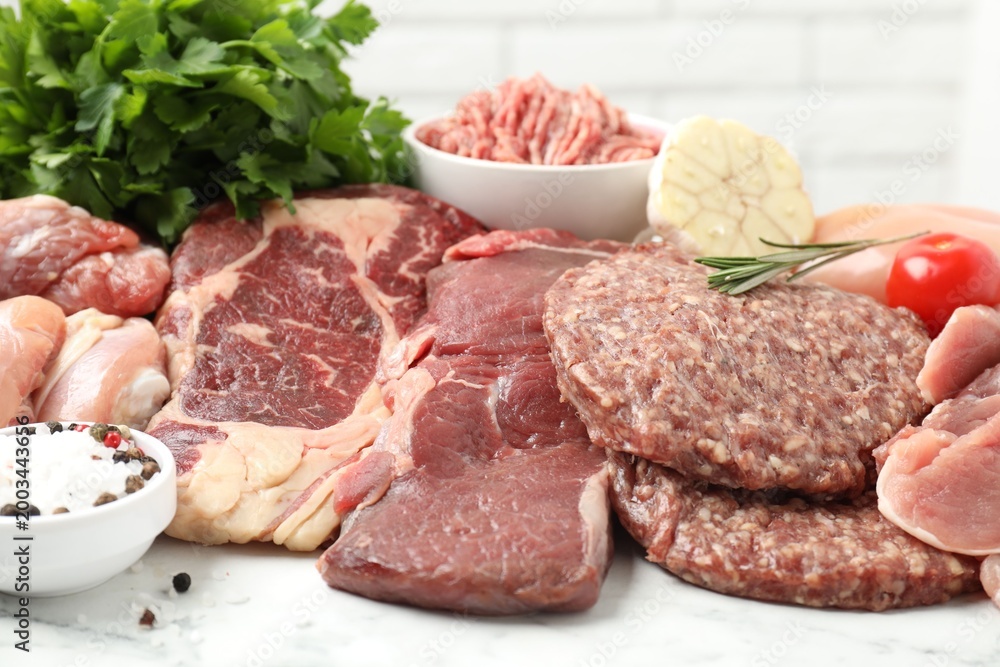 Fototapeta premium Different raw meat products, spices and tomato on table, closeup