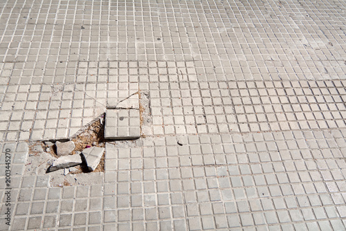 Fotografija Damaged concrete pavement tiles in a mediterranean urban area, highlighting the need for municipal maintenance and city repair projects for better accessibility