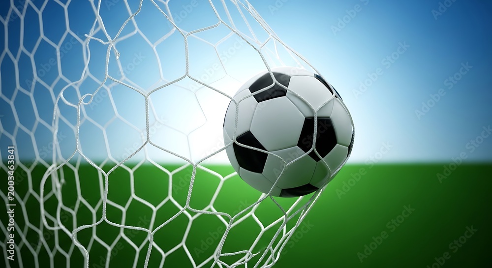 Fototapeta premium Soccer ball flying into goal net on green field with blue sky