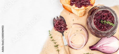 Tableau sur toile Onion jam in glass jar with bread and ingredients on light background with copy