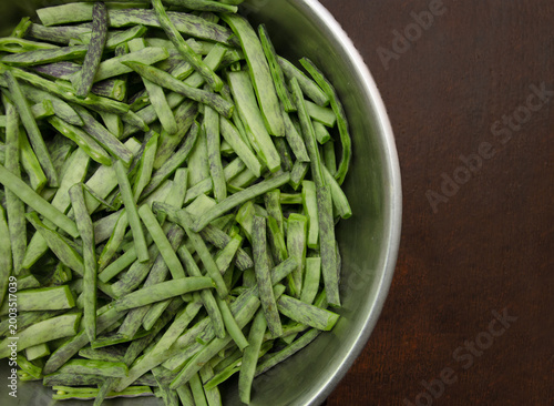Raw green peeled green beans with purple stripes close-up. Raw, peeled organic flat green beans in a bowl on a dark background. Raw vegetables from the garden.