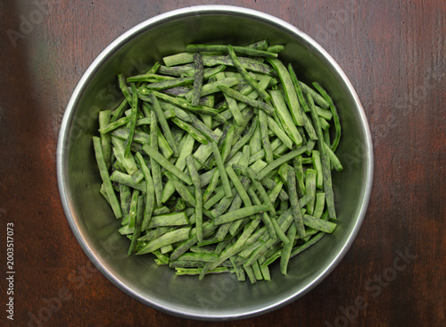 Raw green peeled green beans with purple stripes close-up. Raw, peeled organic flat green beans in a bowl on a dark background. Raw vegetables from the garden.