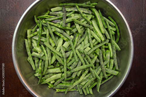 Raw green peeled green beans with purple stripes close-up. Raw, peeled organic flat green beans in a bowl on a dark background. Raw vegetables from the garden.