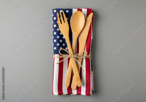Bamboo utensil set wrapped in patriotic American flag napkin on gray background.