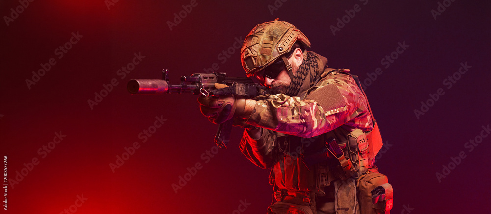 Fototapeta premium Soldier holding rifle on red background with atmospheric smoke. Concept conflict and strength. 