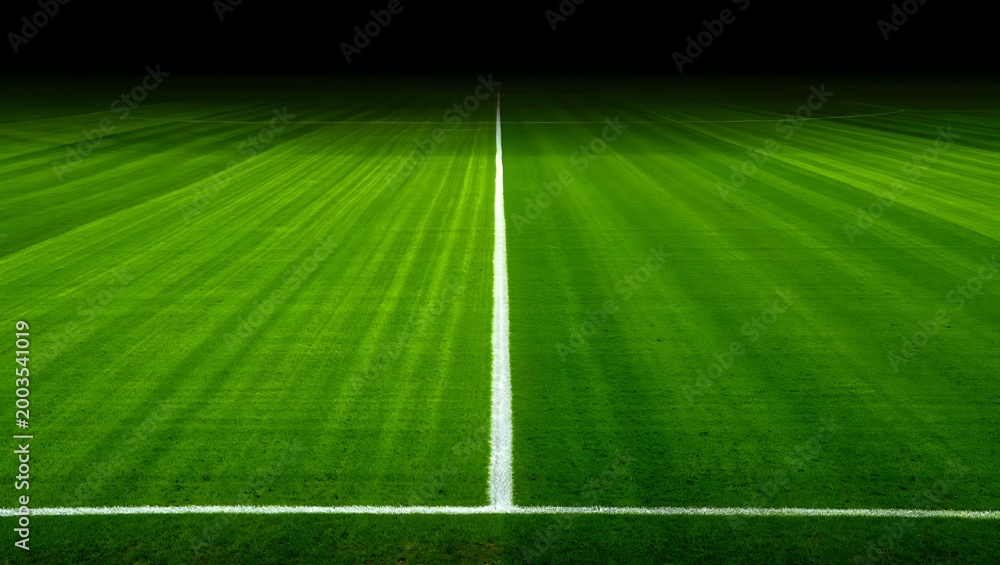 Obraz premium Empty football pitch with central white line and green grass under night stadium lights football competition training