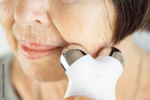 Obraz na plátně biohacking facial rejuvenation senior woman using microcurrent device for skin l