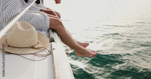 Mature  couple's bare feet hanging off the side of a boat while sailing on the ocean during vacation