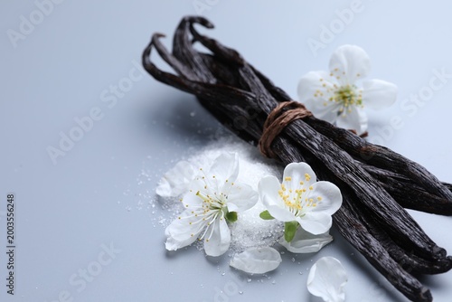 Cuadro en lienzo Aromatic vanilla pods, pile of sugar and flower buds on grey background, closeup