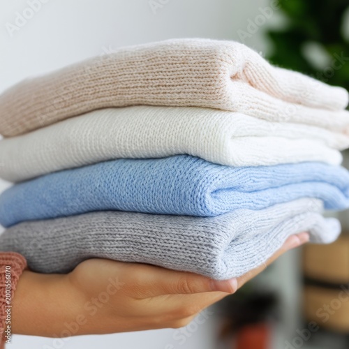 Knit Sweaters Stacked in Hand on a Gray Background With Soft Lighting