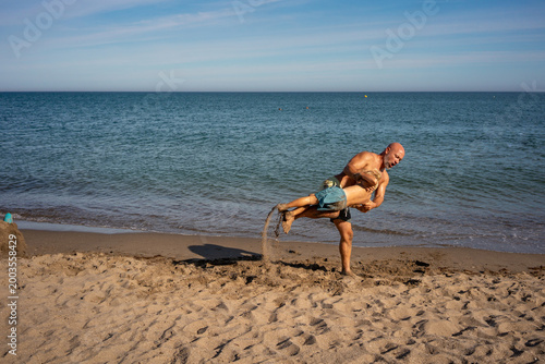 Canvas-taulu Father lifting and spinning his young son playfully on sandy beach by the sea, b