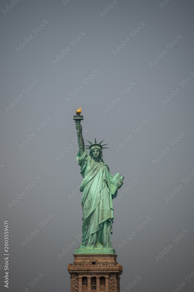 Fototapeta premium New york, usa august 16,2024. Statue of liberty against a gray sky, showing the iconic landmark and symbol of freedom and democracy in the united states