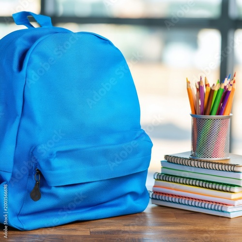 Bright Blue Backpack Sits on a Table Next to Notebooks and Colored Pencils in...