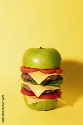 Conceptual Green Apple Double Cheeseburger with Copy Space on Yellow Background