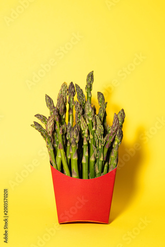 Fresh Green Asparagus in Red Fast Food Box on Vibrant Yellow Background
