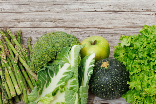 Fresh Green Vegetables and Apple Assortment on Rustic Wooden Background