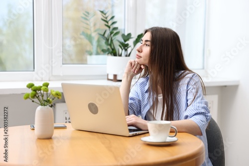 Fotografie Young student studying with laptop at wooden table indoors