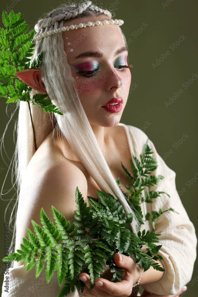 Fototapeta premium Beautiful elf girl with floral decor on dark olive background