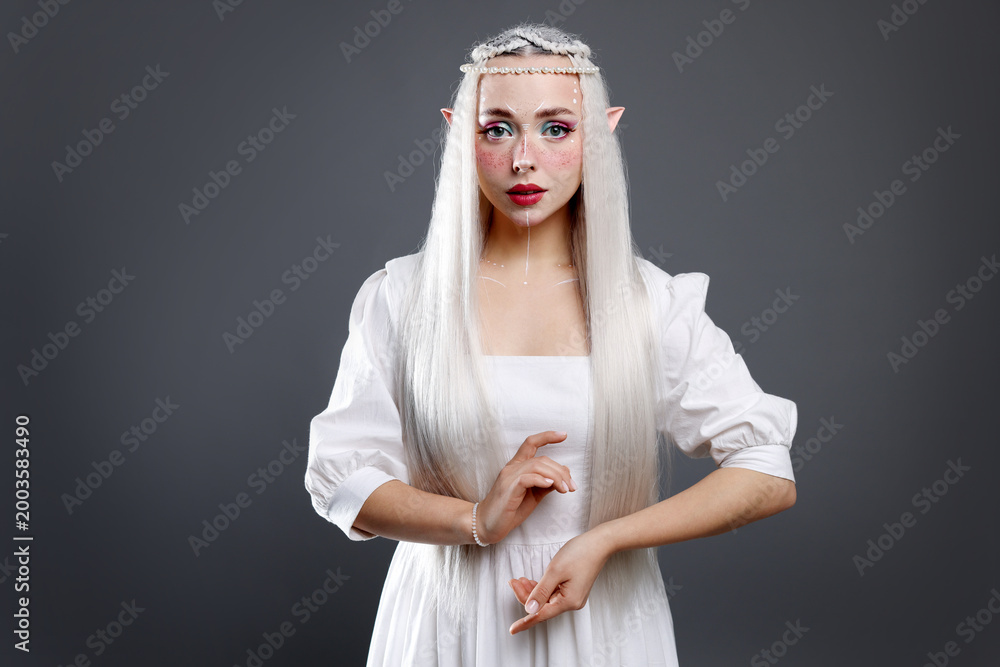 Fototapeta premium Beautiful girl dressed as elf on grey background