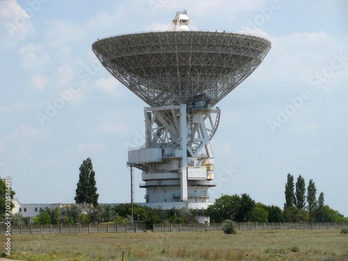 Foto antenna installation site, a large parabolic antenna sits amidst trees and grass
