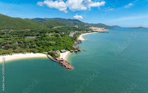 An aerial view of a tropical resort with overwater bungalows and a white sand beach in on Hon Tre Island, Nha Trang, Vietnam. 