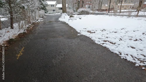 bringing the trash down in driveway partly covered with snow after the snowfall in February