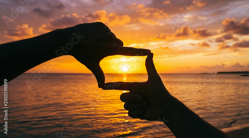 Hands framing the beautiful sunset over the ocean horizon