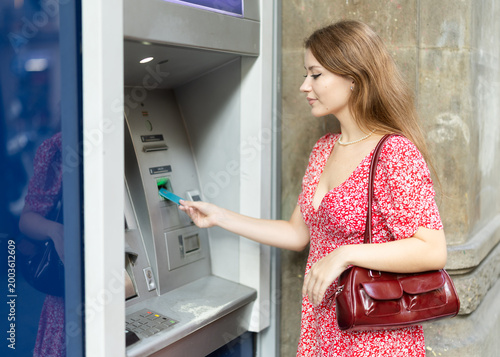 Tableau sur toile Girl uses ATM, withdraws cash from card