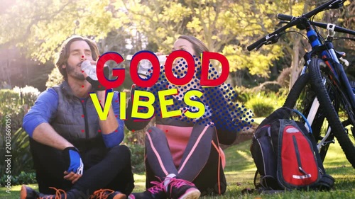 Cycling duo pausing after ride, hydrating with bottles while GOOD VIBES overlay animating over them