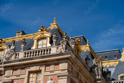 Versailles palace exterior close-up showing detail of statues and gilded roof line