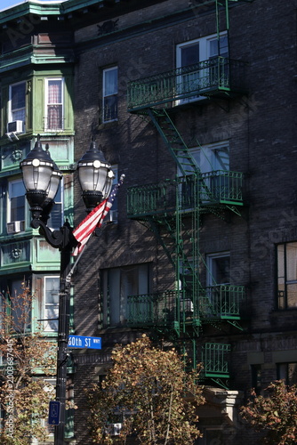 Fotografie Old lamp next to a green fire escape in the city