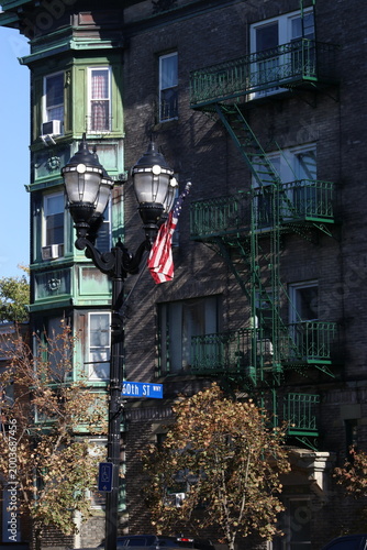 Fotografie Old lamp next to a green fire escape in the city