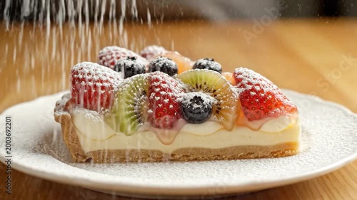 A delicious slice of fruit tart, featuring fresh strawberries, kiwi and blueberries, served on a white plate, ready to eat