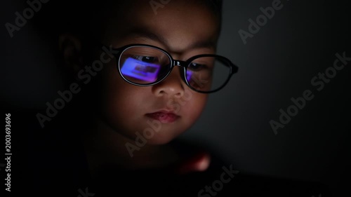 The little boy is using a smartphone at home at night.