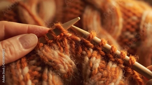 Close-up of hands knitting with orange and white yarn