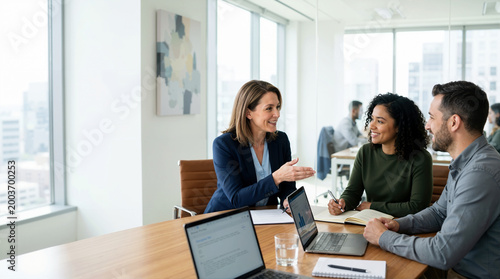 Female corporate manager coaching diverse team members in a modern office. Business colleagues discussing project strategy at a conference table. Leadership and mentoring concept