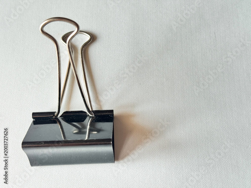 Minimalist black binder clip rests on clean white surface
