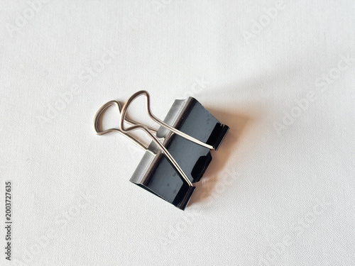Minimalist black binder clip rests on clean white surface