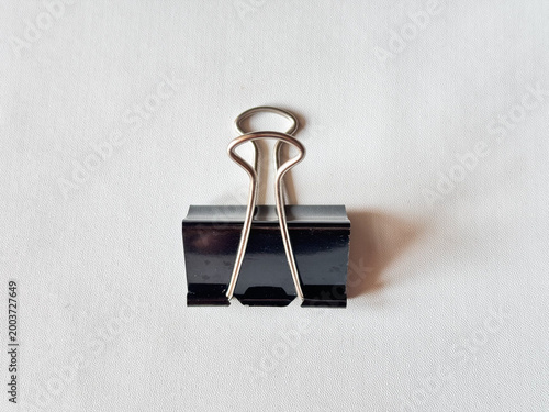 Minimalist black binder clip rests on clean white surface